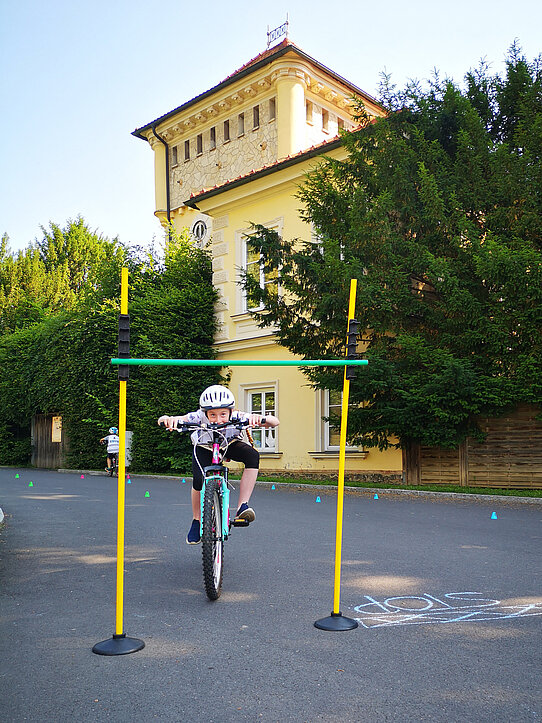 Kind fährt unter Limbostange durch