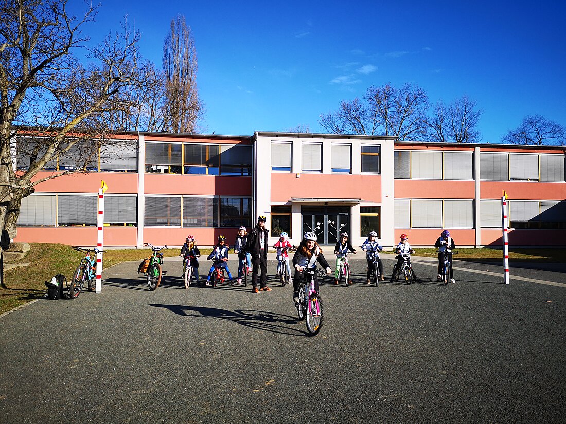 Radfahrtraining im Schonraum, ein Kind fährt während die anderen zusehen